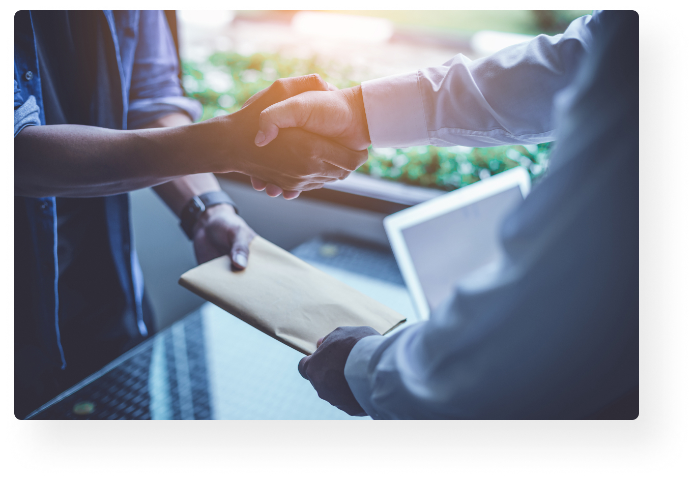 people shaking hands and exchanging an envelope